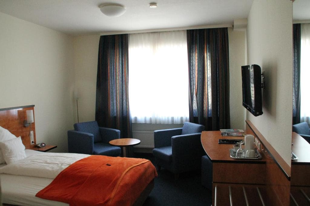 Double room with wall-mounted TV and orange bed throw