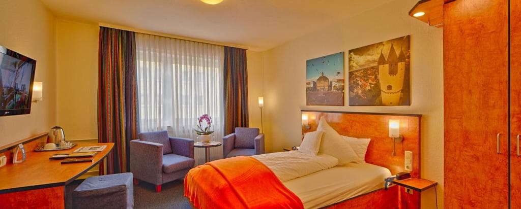 Superior double room with Hanau artwork above the bed, flat-screen TV, and seating area