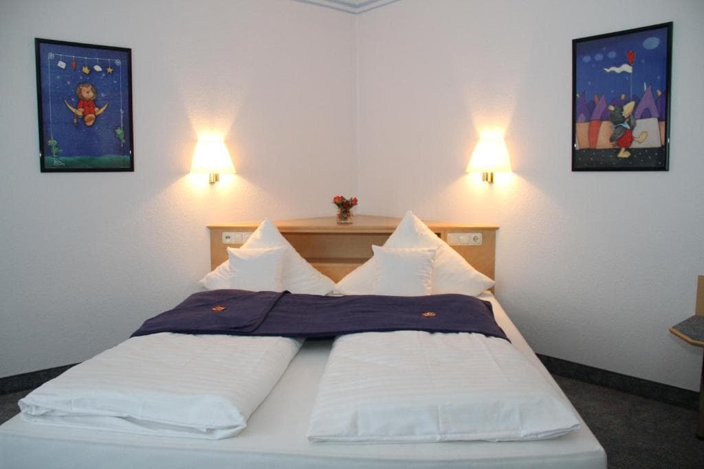 Economy single room with a neatly made single bed and framed children's artwork