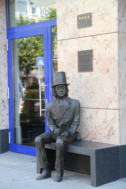 Bronze statue of one of the Grimm brothers seated on a bench at the hotel entrance